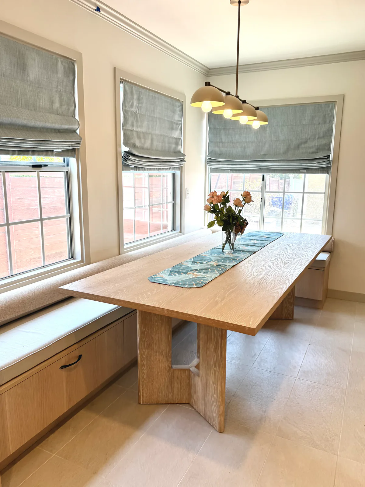 Breakfast nook framed by three windows with linen roman shades
