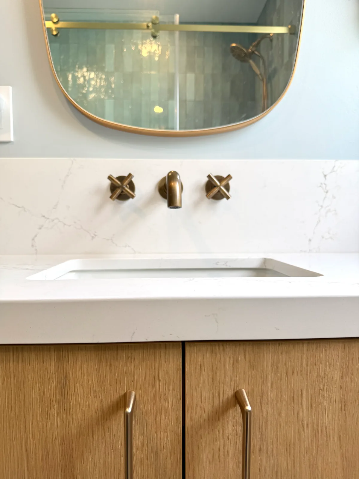 Wall-mount brass cross-handle faucet on a quartz backsplash