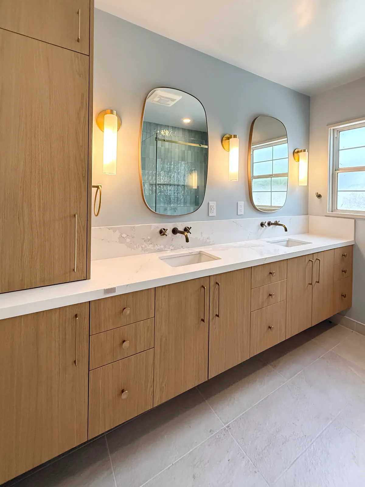 Hall bath double vanity with shaped mirrors and brass sconces