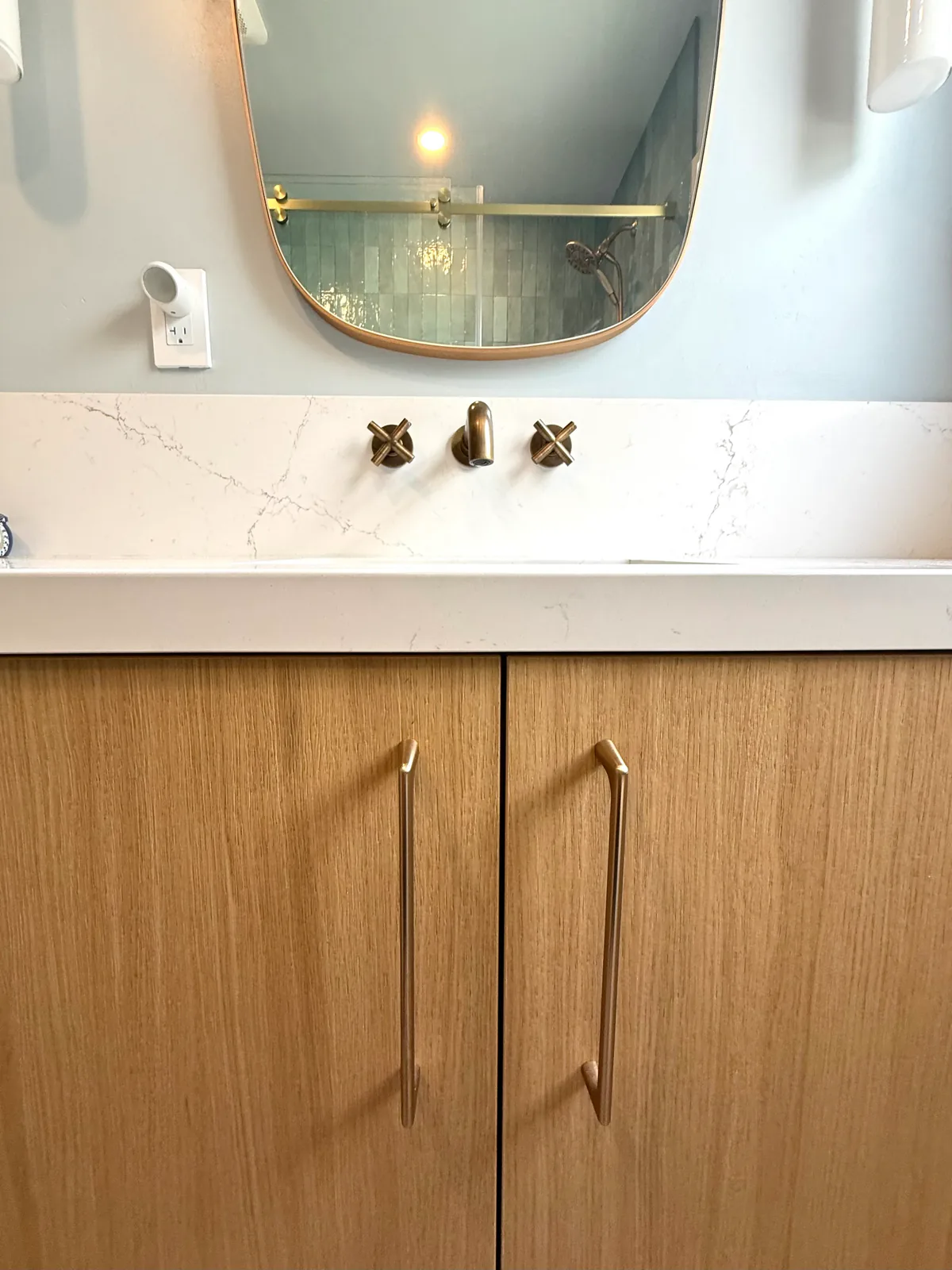 Vanity with brass hardware and rounded mirror