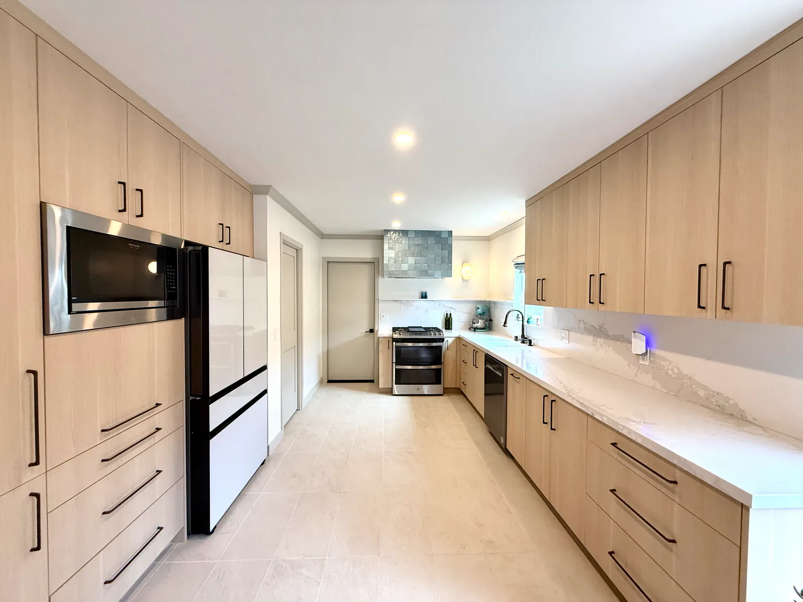 Remodeled galley kitchen with white-oak cabinetry and quartz counters